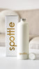 Unboxing einer cremeweißen spottle Thermosflasche aus Metall mit goldenem Logo, Schraubdeckel und hochwertiger Verpackung.